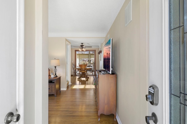 hallway featuring visible vents, baseboards, and wood finished floors