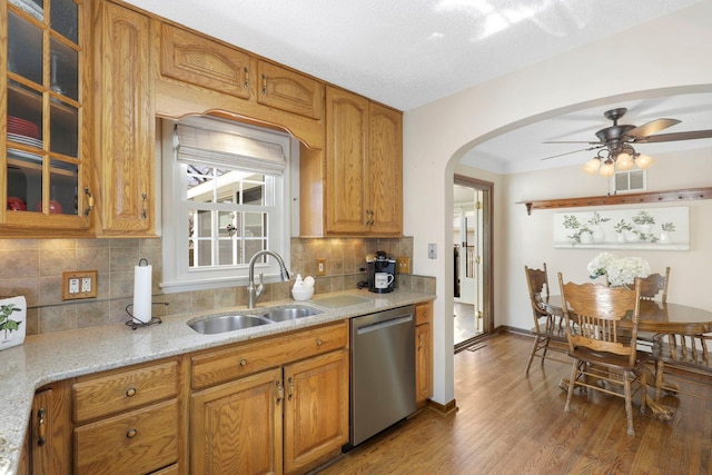 kitchen featuring a ceiling fan, visible vents, arched walkways, a sink, and stainless steel dishwasher