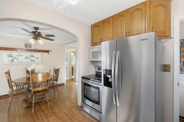 kitchen featuring wood finished floors, visible vents, arched walkways, ceiling fan, and stainless steel appliances