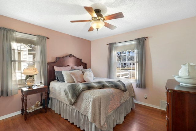 bedroom with visible vents, a ceiling fan, a textured ceiling, wood finished floors, and baseboards