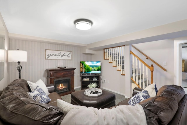 carpeted living area featuring stairway, baseboards, and a glass covered fireplace