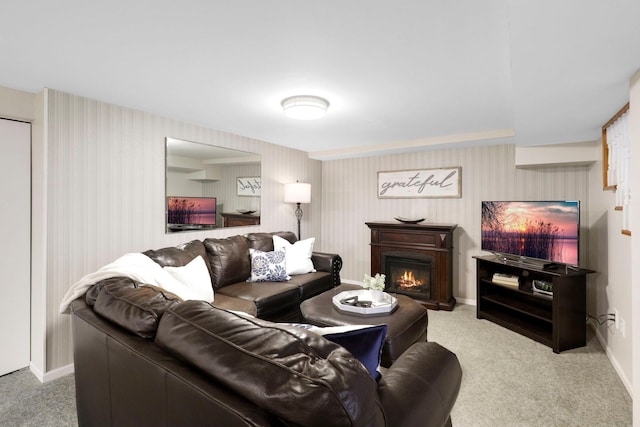 carpeted living room with wallpapered walls, baseboards, and a warm lit fireplace