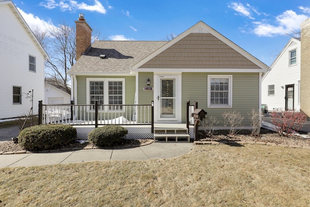 bungalow-style house with a garage, roof with shingles, a porch, and a chimney