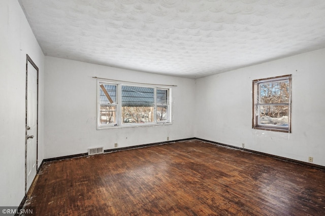 spare room featuring a wealth of natural light, dark hardwood / wood-style flooring, and a textured ceiling