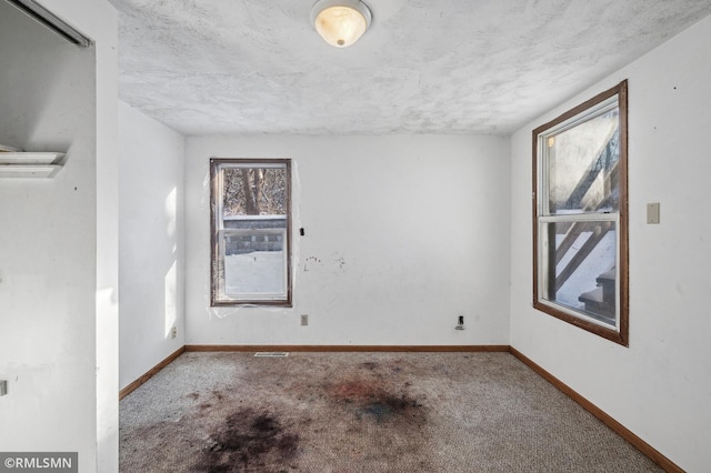 carpeted empty room featuring a textured ceiling