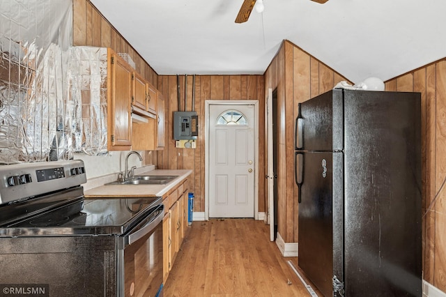 kitchen featuring sink, electric panel, electric range, wood walls, and black fridge