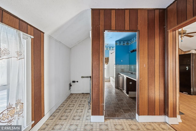 hallway featuring sink, wood walls, and vaulted ceiling