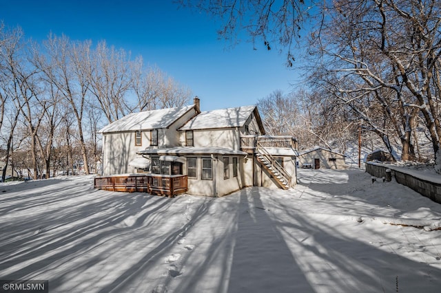 snow covered back of property featuring a wooden deck