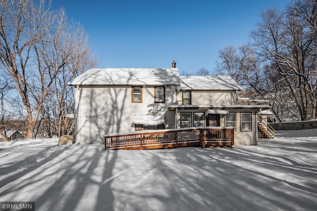 snow covered back of property with a deck