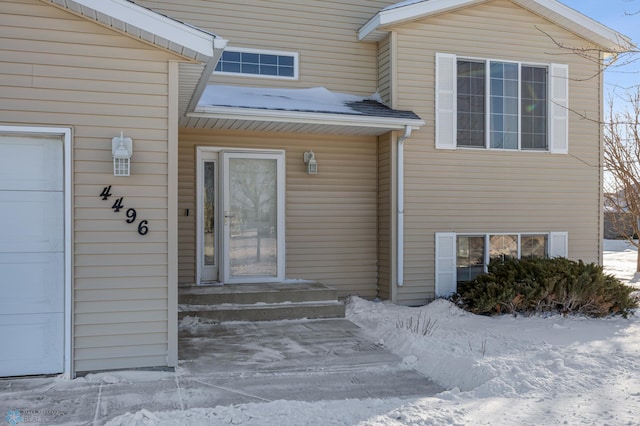 snow covered property entrance with a garage