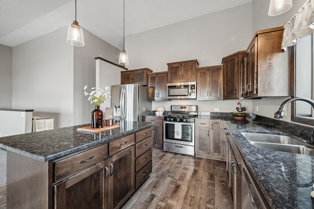 kitchen with appliances with stainless steel finishes, sink, hanging light fixtures, a center island, and dark brown cabinets