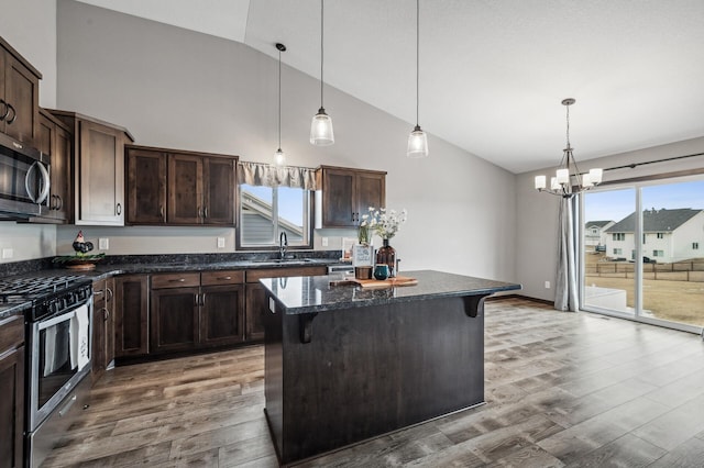 kitchen with pendant lighting, a breakfast bar area, stainless steel appliances, a center island, and dark brown cabinetry