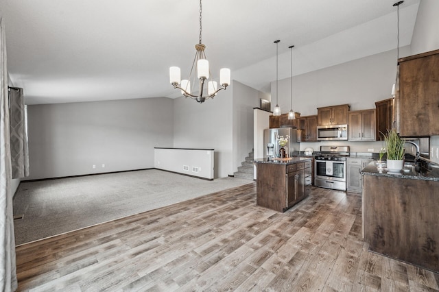 kitchen featuring an inviting chandelier, light wood-type flooring, a kitchen island, pendant lighting, and stainless steel appliances