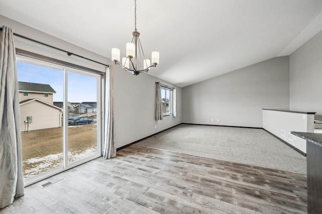 unfurnished dining area featuring lofted ceiling, an inviting chandelier, and light hardwood / wood-style flooring