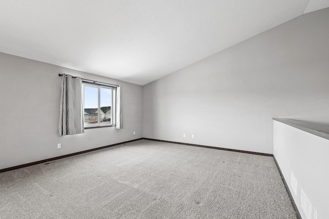 carpeted spare room featuring lofted ceiling