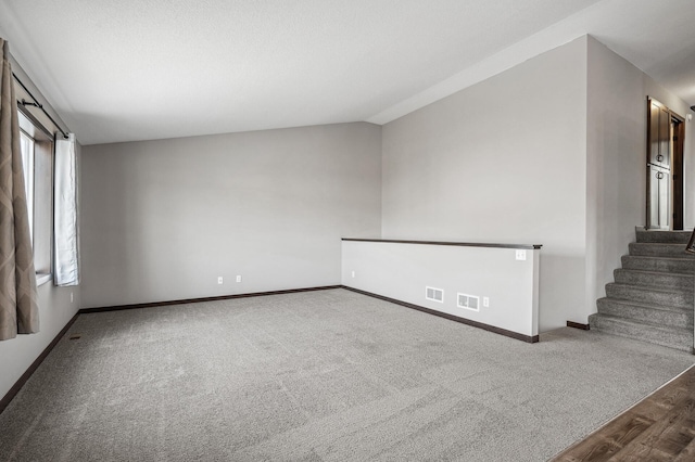 carpeted empty room featuring vaulted ceiling