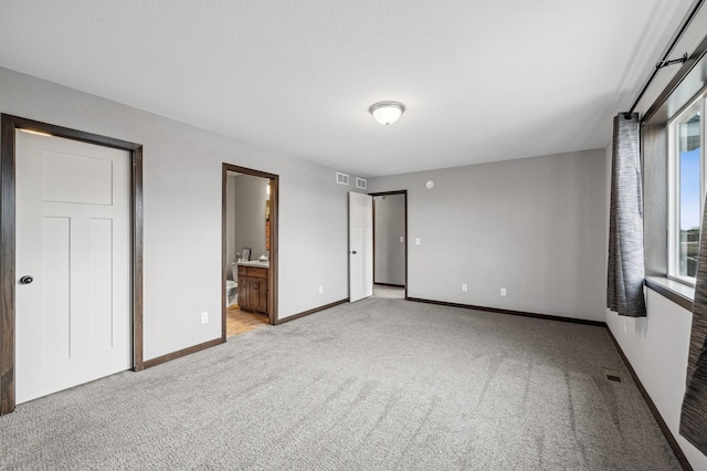 unfurnished bedroom with light colored carpet and ensuite bath