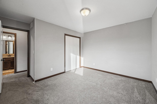 unfurnished bedroom with dark colored carpet, sink, and a closet