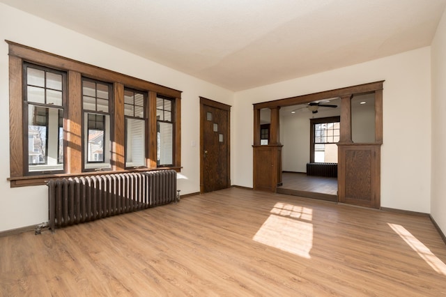 unfurnished room featuring radiator heating unit and light hardwood / wood-style flooring