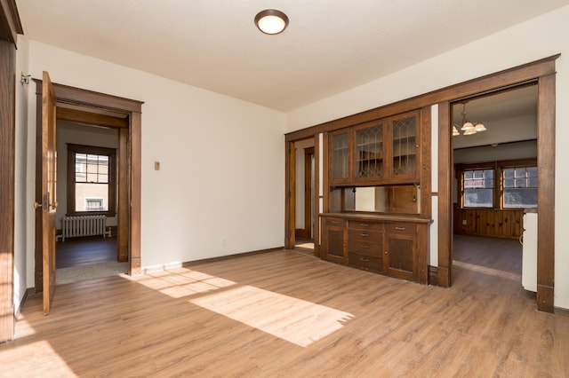 spare room featuring hardwood / wood-style flooring, radiator heating unit, and a chandelier