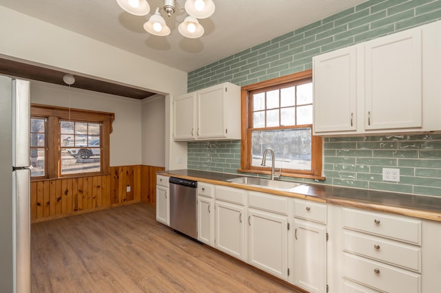 kitchen with sink, light hardwood / wood-style flooring, hanging light fixtures, stainless steel appliances, and white cabinets