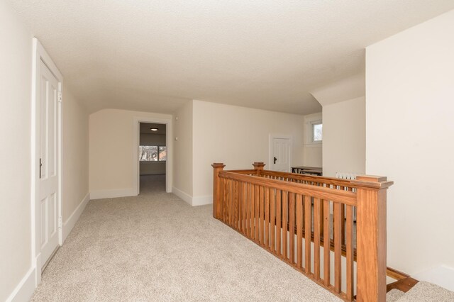 hall with light colored carpet and a textured ceiling