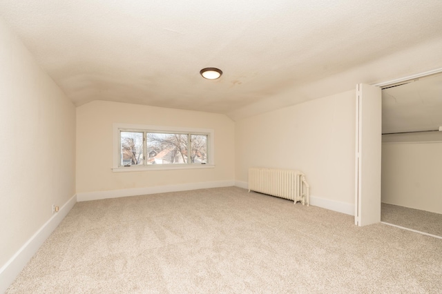 bonus room featuring lofted ceiling, radiator, light carpet, and a textured ceiling