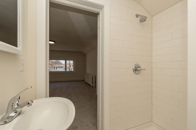 bathroom featuring lofted ceiling, sink, radiator heating unit, and tiled shower