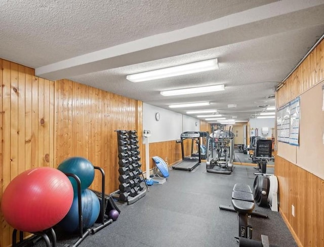 exercise room featuring a textured ceiling and wood walls