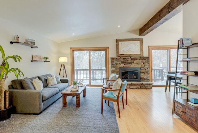 living room with vaulted ceiling with beams, plenty of natural light, a fireplace, and light wood-type flooring