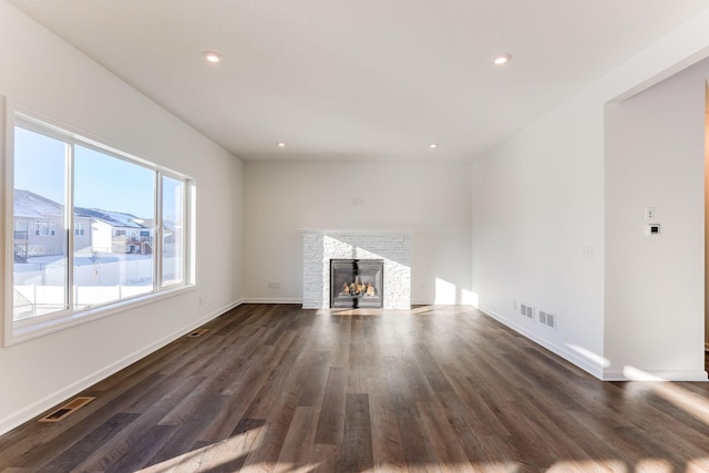 unfurnished living room featuring dark wood-style flooring, a fireplace, and visible vents