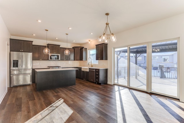 kitchen with a kitchen island, decorative light fixtures, stainless steel appliances, light countertops, and a sink