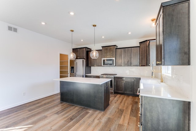 kitchen featuring stainless steel appliances, light countertops, a kitchen island, and visible vents