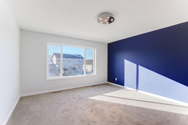 empty room featuring visible vents, baseboards, and light colored carpet