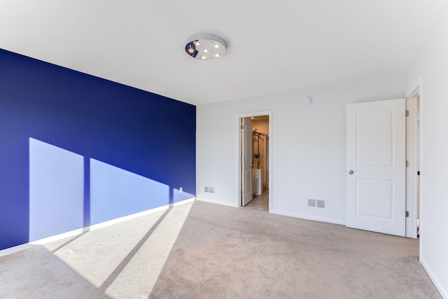 spare room with light carpet, visible vents, and baseboards