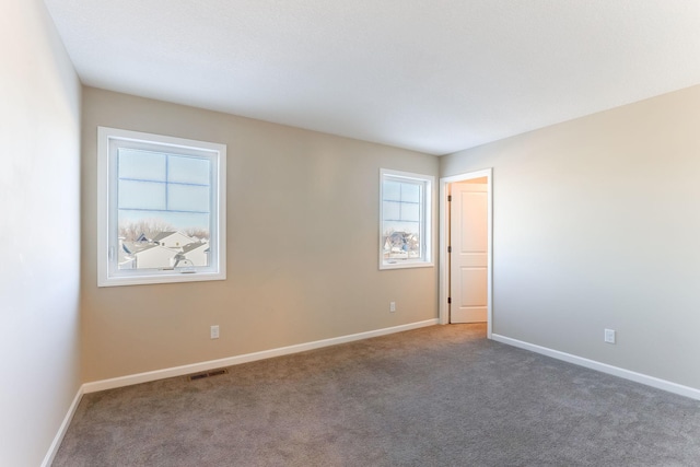 unfurnished room featuring carpet, plenty of natural light, visible vents, and baseboards