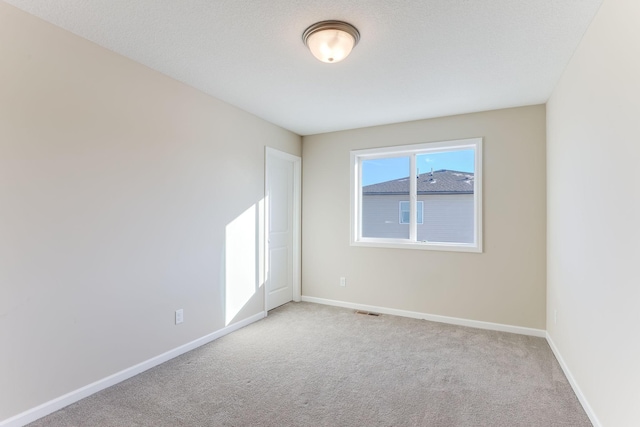 spare room featuring baseboards, visible vents, and light colored carpet