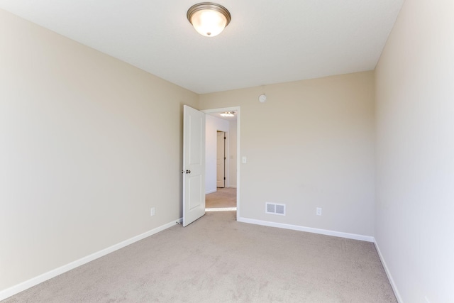 unfurnished room with light colored carpet, visible vents, and baseboards