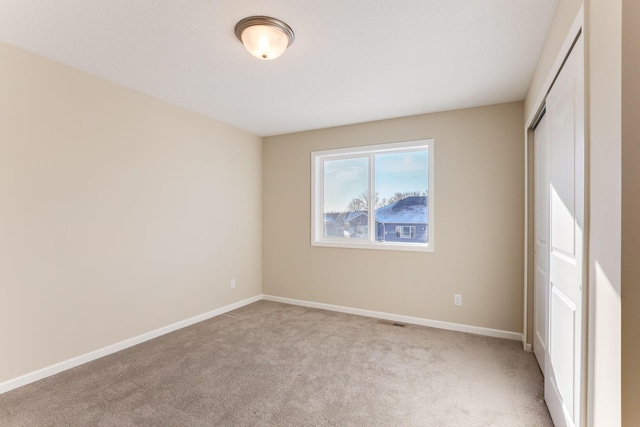 unfurnished bedroom featuring light carpet, visible vents, baseboards, and a closet