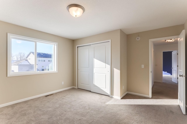 unfurnished bedroom with a closet, light carpet, visible vents, and baseboards