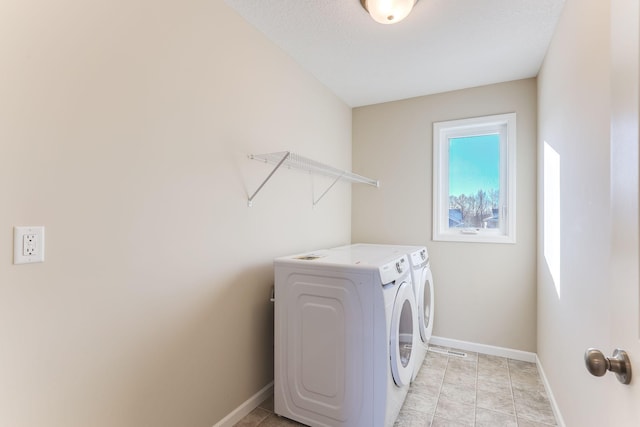 clothes washing area featuring laundry area, light tile patterned floors, baseboards, and separate washer and dryer