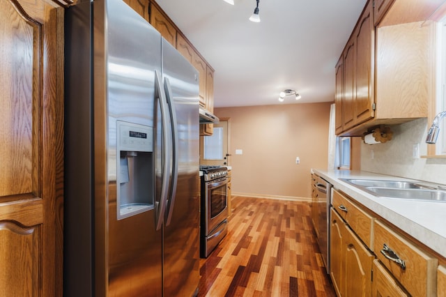 kitchen featuring sink, hardwood / wood-style floors, appliances with stainless steel finishes, and decorative backsplash