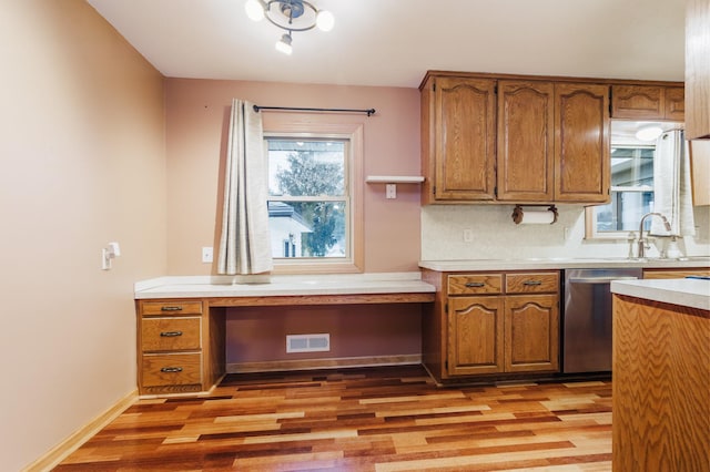 kitchen featuring sink, light hardwood / wood-style flooring, stainless steel dishwasher, and tasteful backsplash