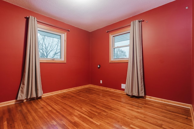 spare room featuring light wood-type flooring and a textured ceiling