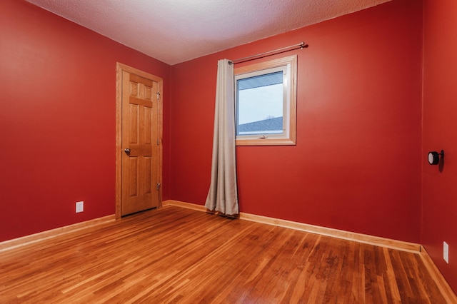 spare room featuring hardwood / wood-style floors and a textured ceiling