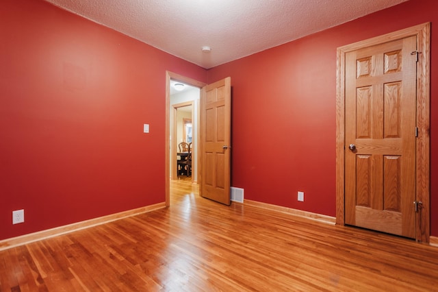 spare room featuring a textured ceiling and light wood-type flooring