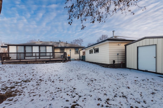 snow covered house featuring a deck and a storage unit