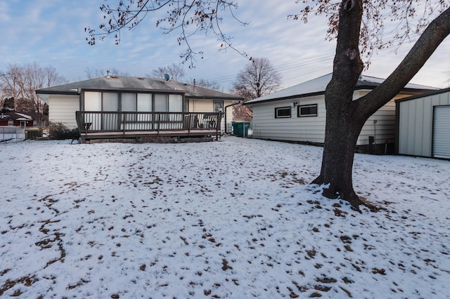 snow covered house with a deck and a shed