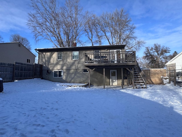 snow covered back of property with a wooden deck