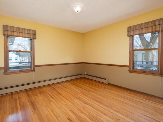 unfurnished room with baseboard heating and light hardwood / wood-style flooring